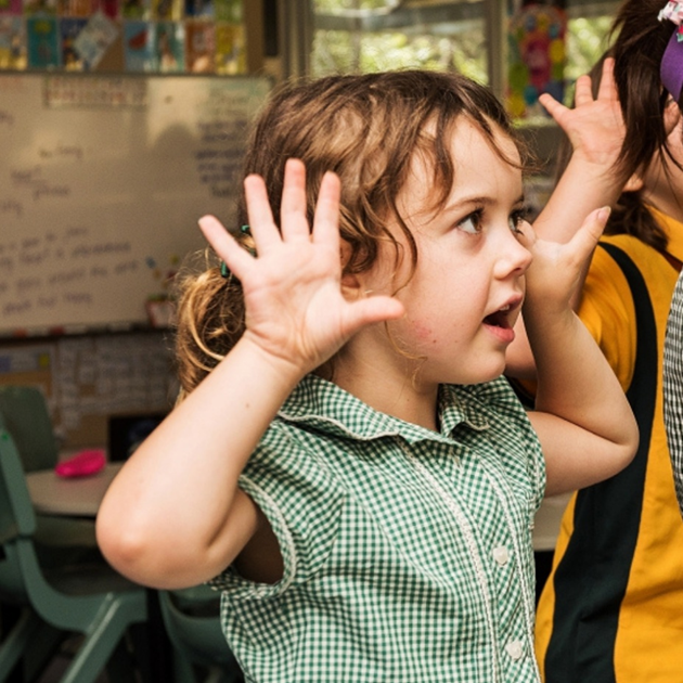 student with hands up singing