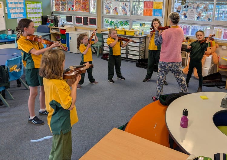 students playing violin with a teacher